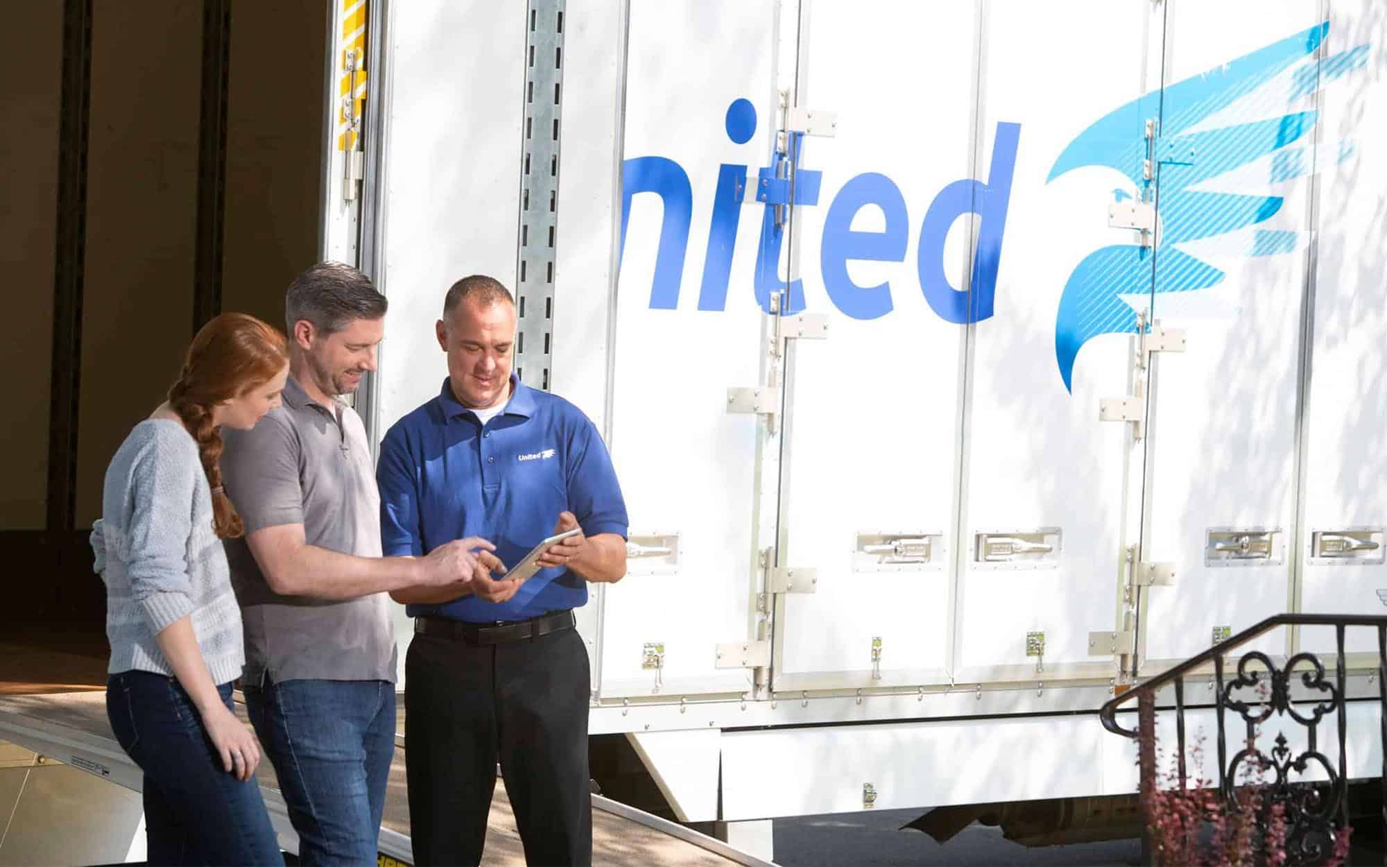 Side view of a couple with moving professional talking next to United branded truck