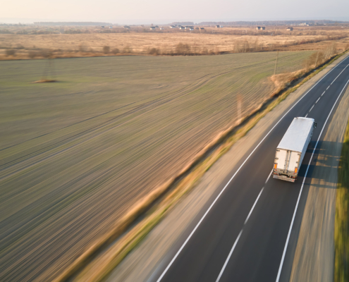 Aerial view of blurred fast moving semi-truck with cargo trailer driving on highway