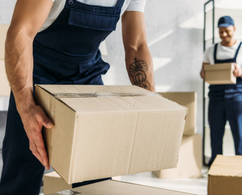 Front view of tattooed worker in uniform holding carton box