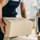 Front view of tattooed worker in uniform holding carton box