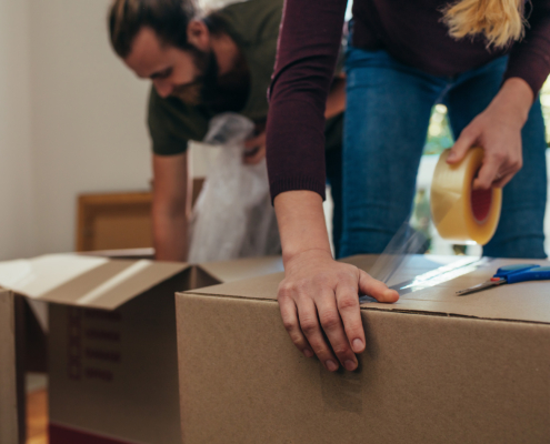 Close up of a woman applying adhesive tape on a packing box